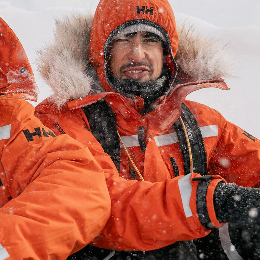 Mann i oransje vinterjakke i snøvær